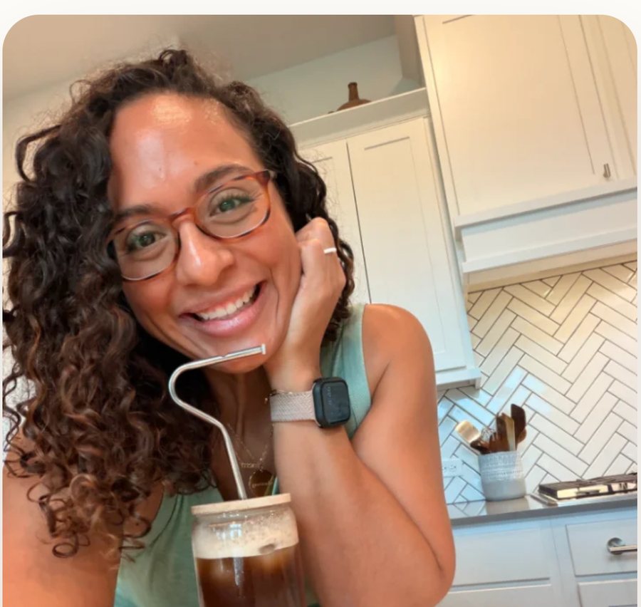 Susana Demore smiling in her kitchen with an iced coffee